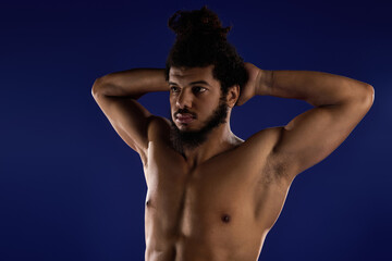 Fototapeta premium Athletic African American man demonstrates strength against a blue background