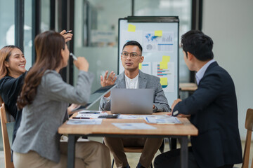Group of Asian businesspeople sits down for a business investment planning meeting.	