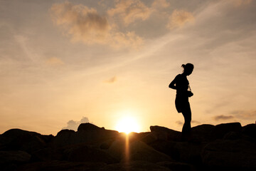 Silhouette of a Woman Photographer at Sunset on a Rocky Shore