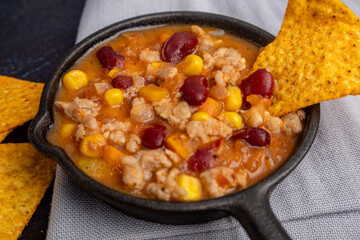 Chili con carne in a skillet with triangular nachos