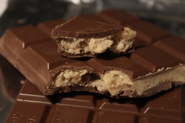 Milk chocolate bars with visible peanut filling displayed on chocolate base showing broken pieces and creamy interior texture