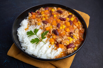 Chili con carne with rice in a black bowl