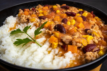 Chili con carne with rice on a dark background