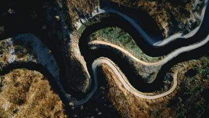 Aerial view of a winding mountain road with tight switchbacks cutting through rugged terrain. Concept Aerial landscape photography, Winding mountain road switchbacks, Rugged mountainous terrain