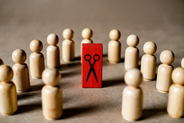 A Minimalist Business Concept Photograph of Wooden Figures Surrounding a Red Scissor Symbol Block