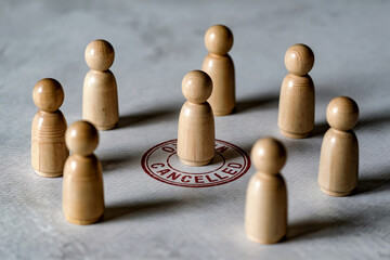 A Photograph of Wooden Peg People Figures Surrounding a Central Figure with a "Cancelled" Stamp Mark