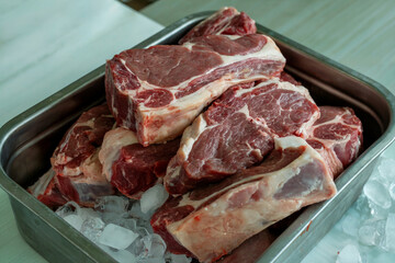 A Close-Up Photograph of Raw Meat Cuts Including Steak Placed in a Metal Tray on a Bed of Ice