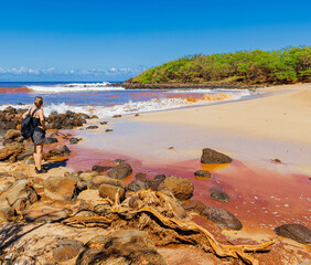 Female Hiker Watching Red Waves Caused By Red Dirt on Kaunala Beach, Molokai, Hawaii, USA