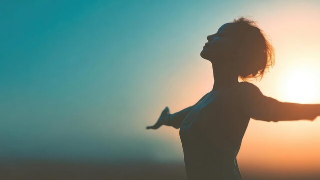 Silhouette of a person with arms outstretched at sunrise against a teal to orange sky. Concept Silhouette Portraits, Sunrise Photography, Teal to Orange Sky, Raised Arms Pose, Golden Hour