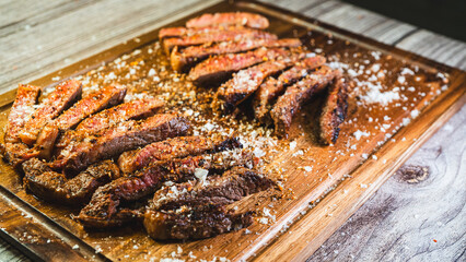 Beautifully sliced rare ribeye steak on a wooden board, showing perfect pink interior and golden...