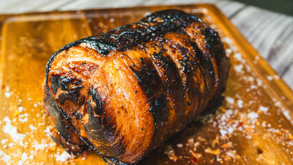 Whole pork chashu roll on a wooden board, perfectly toasted and golden brown outside. Ready to slice for ramen bowls. Marinated, tender, and aromatic.