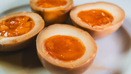 Soy-marinated ajitsuke tamago eggs halved on a plate, revealing creamy, succulent yolks. Perfect for ramen topping or appetizer. Rich, flavorful, and authentic.