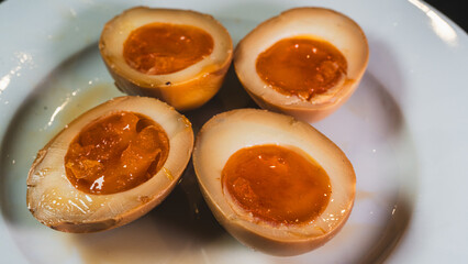 Soy-marinated ajitsuke tamago eggs halved on a plate, revealing creamy, succulent yolks. Perfect for ramen topping or appetizer. Rich, flavorful, and authentic.