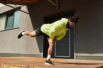Sportive man in vibrant green hoodie exercises outdoors with focus and determination