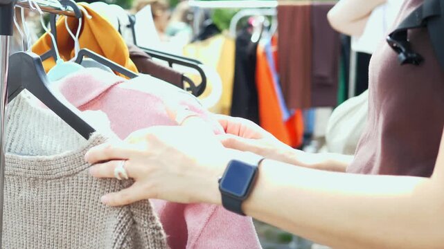 A woman browsing clothes at a flea market, embracing conscious consumption and sustainable fashion