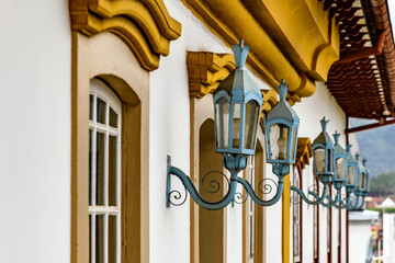 Antique metal lanterns decorating the facade of a historic colonial-style house in the city of Ouro Preto.