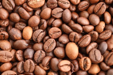 Big pile of fresh roasted brown coffee beans as flat background photo image with visible details close up