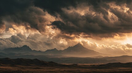 Dramatic, brooding storm clouds illuminate rugged mountain peaks at sunset over a desolate plain