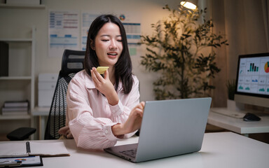 Woman records a voice message on her phone during remote work at night.