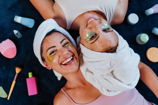 Two happy women lying down, enjoying beauty treatment with under eye patches