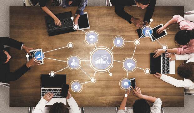 A diverse team collaborates around a wooden table, utilizing laptops and tablets in a modern workspace, enhancing data-driven decisions through technology graphics. Tessel - Powered by Adobe