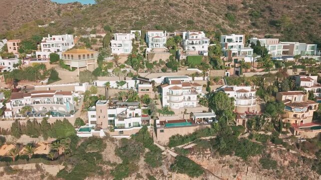 Drone footage of luxury Mediterranean houses and villas on cliffs overlooking the turquoise sea in Moraira, Spain. Scenic view of Costa Blanca architecture and coastline.