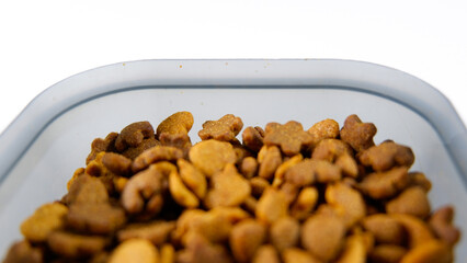Dry pet food close up, cat kibble pile in gray plastic bowl isolated on white background