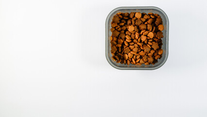 Flat lay view of Dry pet food, cat kibble pile in gray plastic bowl isolated on white background