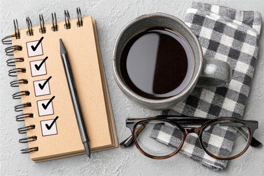 A cup of black coffee sits next to a checklist, pen, and reading glasses, suggesting a productive start to the day