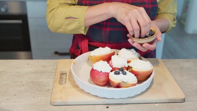 4K close-up video woman cooking beaked apples with cotage cheese decorating with blueberry homemade baking process Fresh ingredients, healthy food nutritious dessert, cooking at home nutrition concept