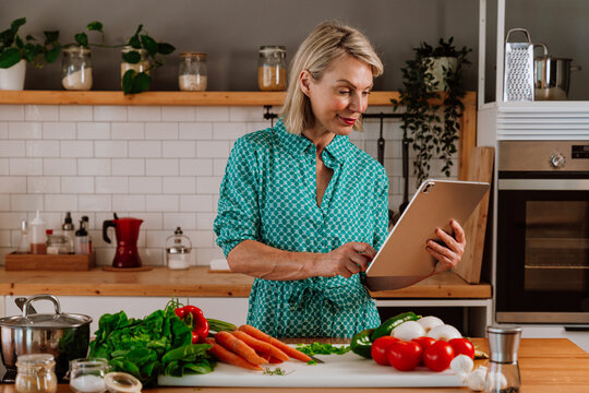 Woman using digital tablet while preparing ingredients in kitchen