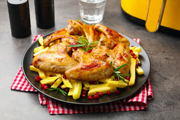 Delicious grilled chicken wings with french fries and air fryer on grey table, closeup