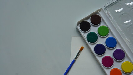 Watercolor paints and brushes on a white background, view from above