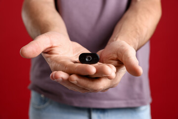 Man with hidden spy camera on red background, closeup