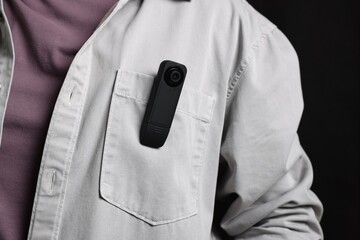 Man with hidden spy camera in his pocket on black background, closeup