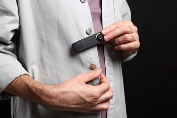 Man with hidden spy camera on black background, closeup