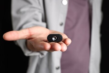 Man with hidden spy camera on black background, closeup