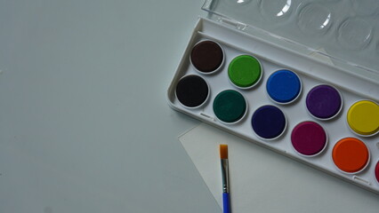 Watercolor paints and brushes on a white background, view from above