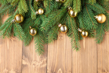 Christmas tree branches with baubles on wooden table, flat lay. Space for text