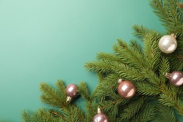 Christmas tree branches with baubles on green background, flat lay. Space for text