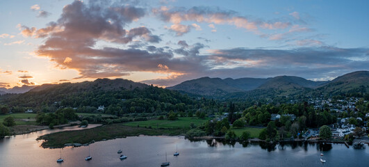 elevated view of sunset over lake windermere at waterhead ambleside looking over the town towards the hill range known as the fairfield horseshoe