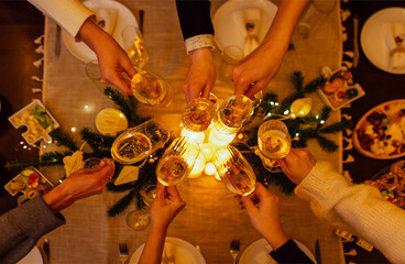 Close-up of female and male hands holding elegant glasses of champagne. Friends clink glasses of sparkling wine. Top of view.