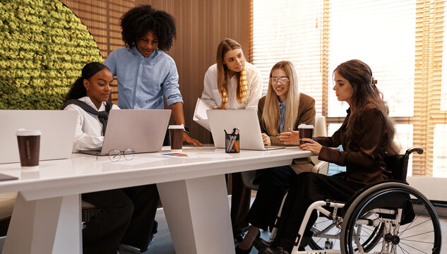 Inclusive diverse business team meeting with woman using wheelchair at modern office