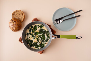 Omelette with spinach in a frying pan, copy space, top view