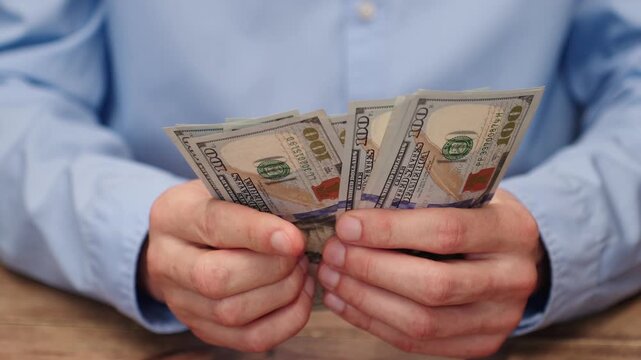 Man counting 100 US dollar bills in close-up. Investment or investor concept for wealth building, financial planning or income