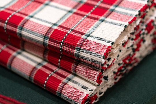 Folded red tartan textiles stacked neatly; rich weave and selective focus evoke Christmas and New Year 2026 lifestyle table styling, soft goods retail and cozy décor stories.