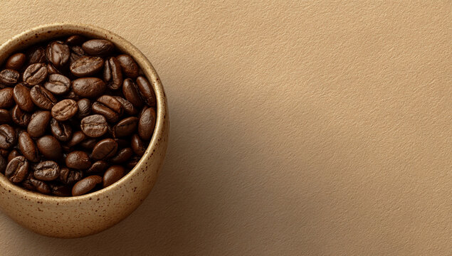 Close up of roasted coffee beans filling a golden scoop on a textured brown background