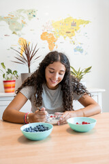 Smiling young woman eating yogurt with fresh berries at home