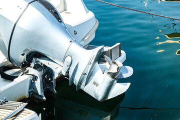 Close-up detail of outboard motor and propeller on docked marine boat, elevated above the water © varbenov
