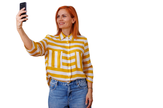 Woman with red hair smiling and taking a selfie using a smartphone, posing on transparent background